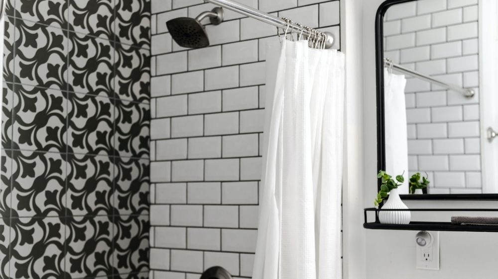 Διακόσμηση μπάνιου με ντουζιέρα σε ασπρόμαυρο σχέδιο με κουρτίνα και δίπλα της καθρέπτης.