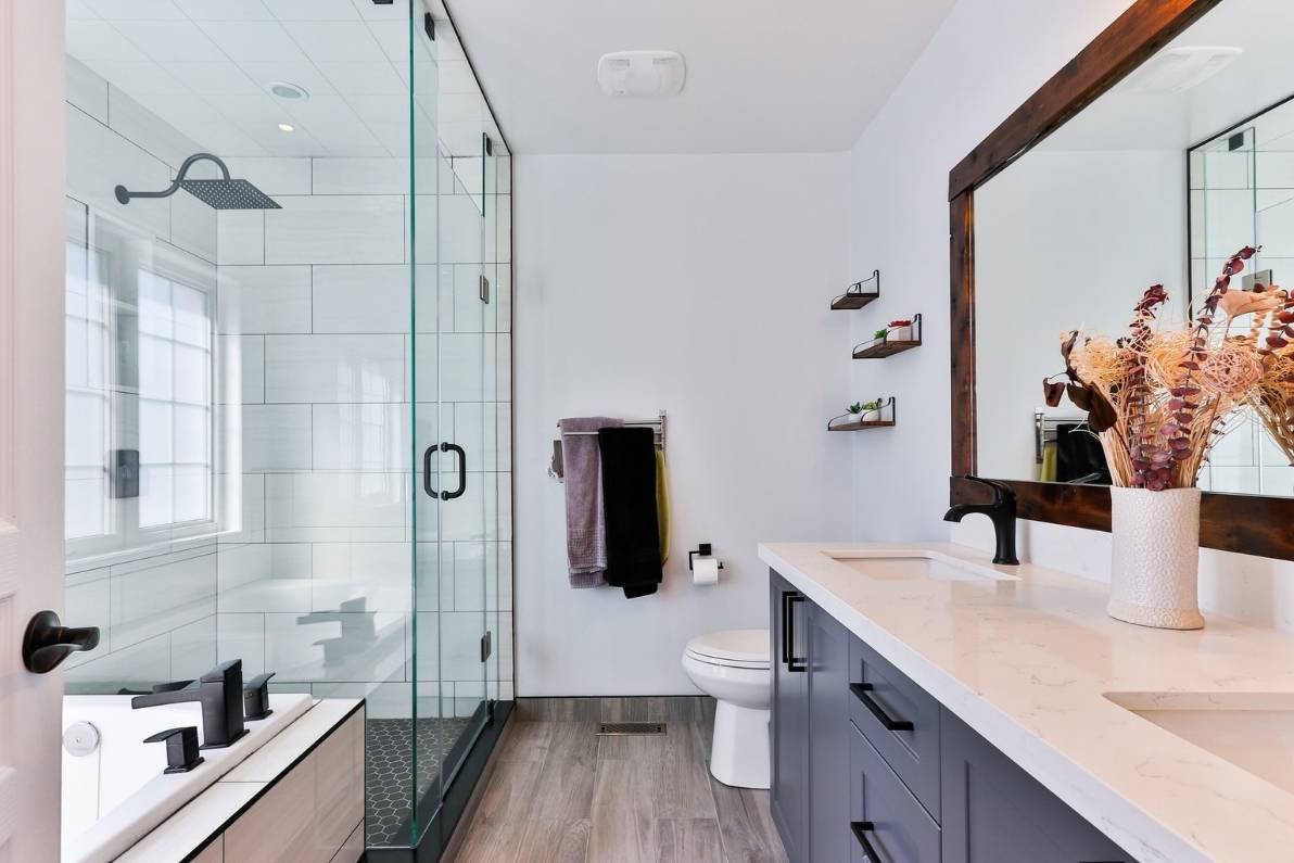 Σύγχρονο και λειτουργικό μπάνιο με ξύλινο δάπεδο και διάφανο κουβούκλιο ντουζιέρας.