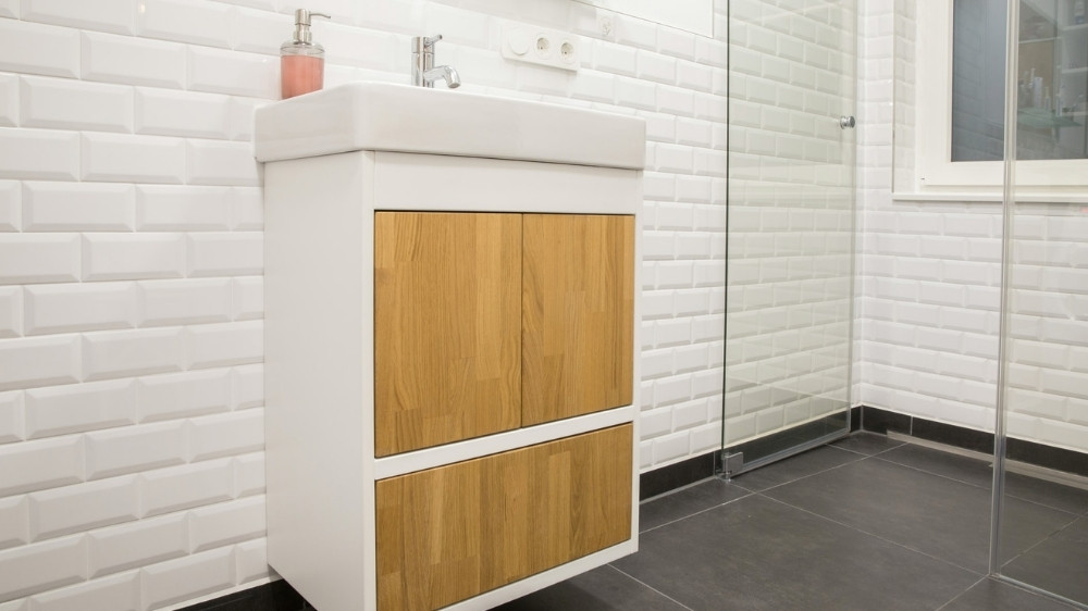 Καφέ, ξύλινο έπιπλο με ντουλάπια μπάνιου πάνω σε σκουρόχρωμα πλακάκια.