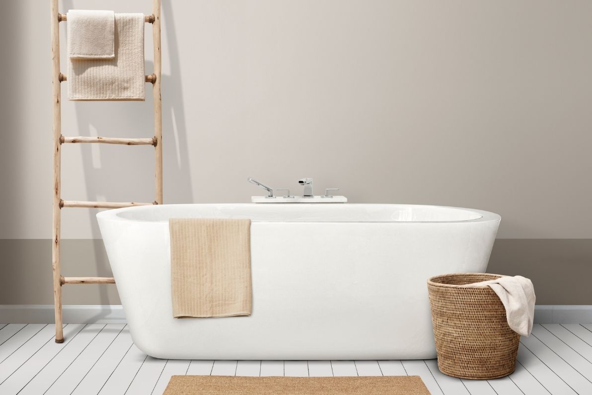 Όμορφο μπάνιο με λευκή μπανιέρα με καφέ πετσέτα και λεπτή διακοσμητική σκάλα στο φόντο.