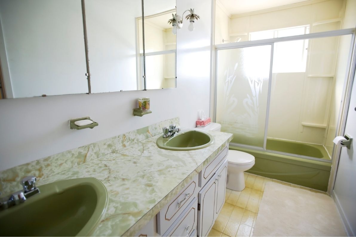 Μοντέρνο μπάνιο με μάρμαρο, καμπίνα ντουζιέρας και δύο πράσινους νιπτήρες.