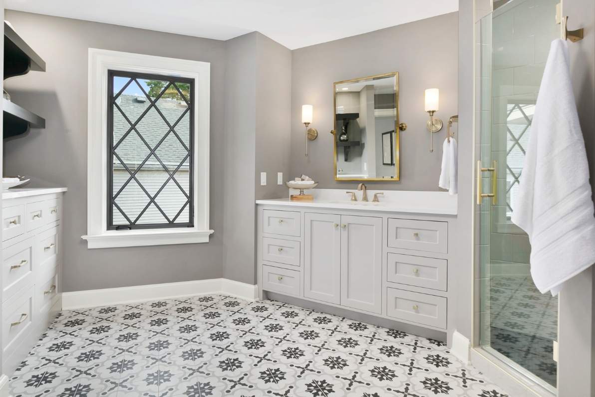 Λευκό μοντέρνο μπάνιο με πλακάκια με ασπρόμαυρο σχέδιο, συρταριέρα και καμπίνα ντουζιέρας.