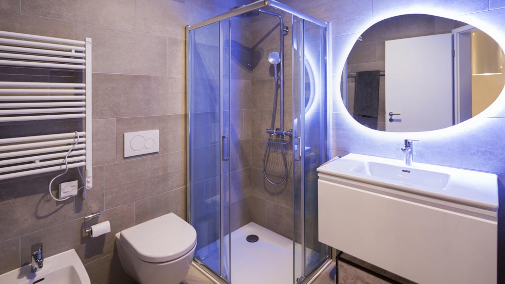 Στρογγυλός καθρέπτης μπάνιου που φωτίζεται από πίσω με κρυφό μπλε LED φωτισμό.