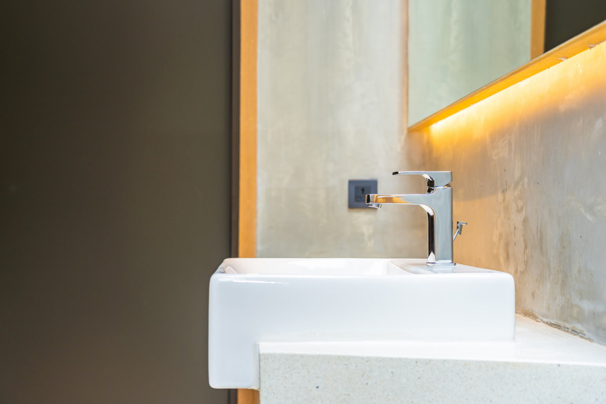 Λευκός νιπτήρας μπάνιου πάνω από τον οποίο βρίσκεται καθρέφτης. Concept για ιδέες φωτισμού μπάνιου.