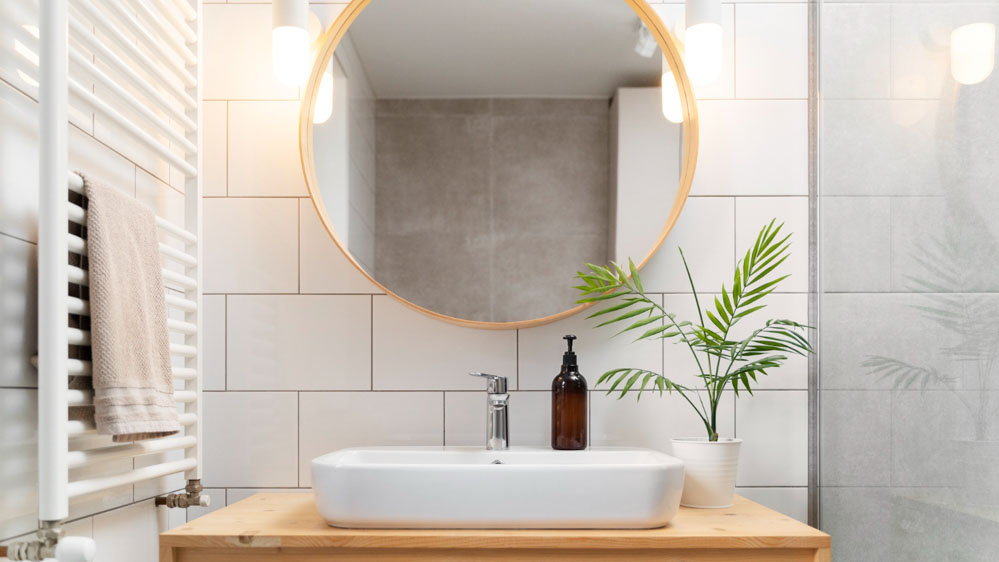 Γκρι απλίκες μπάνιου βρίσκονται και στις δύο πλευρές ενός στρόγγυλου καθρέφτη, φωτίζοντάς τον συμμετρικά.