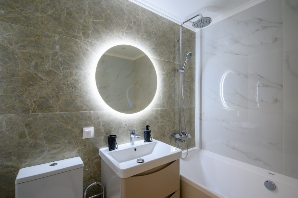 Στρογγυλός καθρέφτης μπάνιου με κρυφό φωτισμό led πάνω από νιπτήρα.