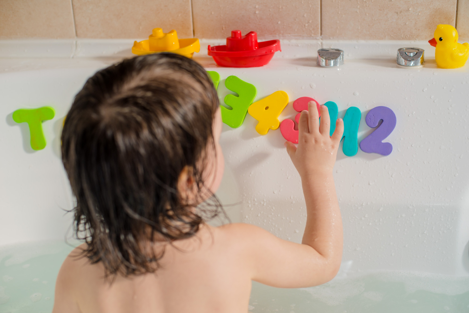 : Θεματική εικόνα για παιδικό μπάνιο και διακόσμηση. Μικρό παιδάκι στην μπανιέρα παίζει με πολύχρωμα γράμματα και αριθμούς.