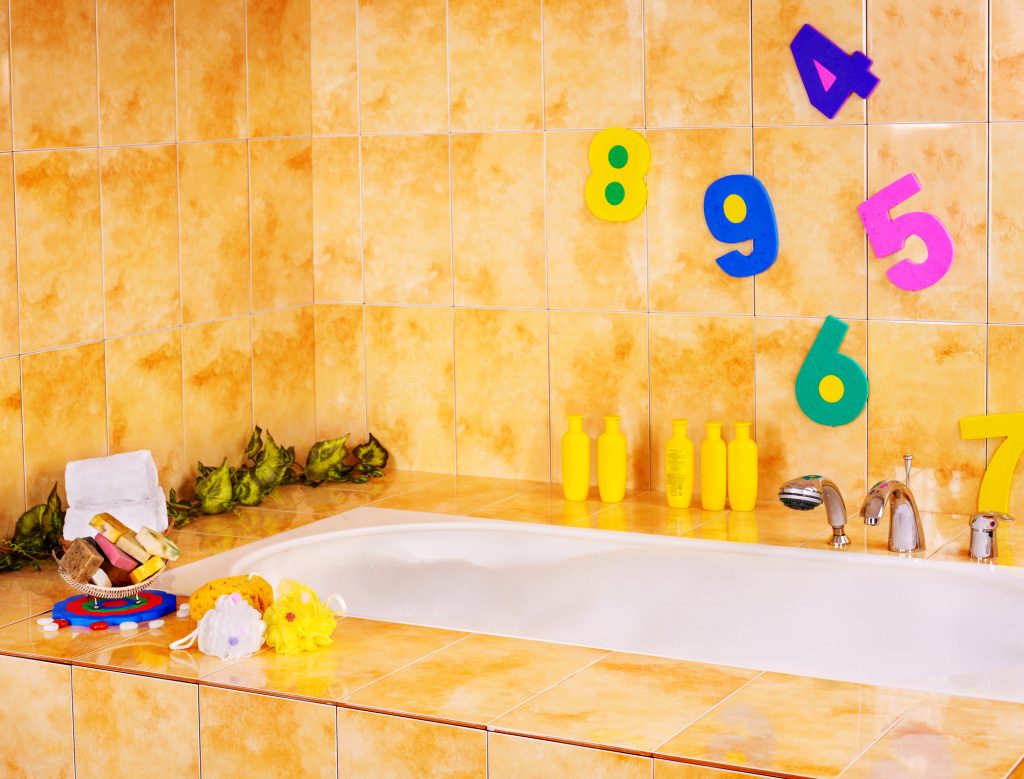 Πολύχρωμοι, μαγνητικοί αριθμοί είναι κολλημένοι σε τοίχο παιδικού μπάνιου.
