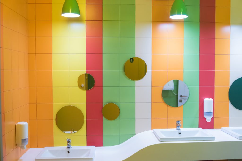 Πολύχρωμα πλακάκια σε τοίχο μπάνιου. Φαίνονται κόκκινα, πορτοκαλί, πράσινα, κίτρινα και άσπρα πλακάκια.