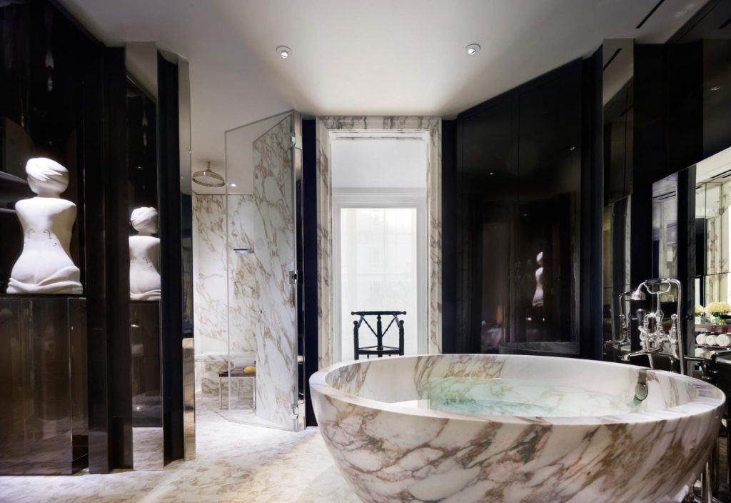 Θεματική εικόνα για ιδέες για πολυτελές μπάνιο. Στρόγγυλη μαρμάρινη μπανιέρα στο κέντρο ενός μπάνιου μαύρης απόχρωσης.